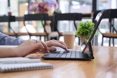 Kahve dükkanında bilgisayar tabletiyle çalışan kırpılmış bir iş kadını..