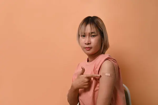 Aziatische Vrouw Zit Beige Achtergrond Toont Haar Arm Met Verband — Stockfoto