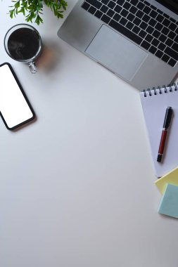 Üst görünüm cep telefonu, dizüstü bilgisayar ve beyaz masadaki defter gibi..