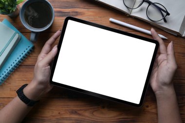 Kapalı görüşlü kadın elinde tabletle tahta masada beyaz ekran tutuyor..