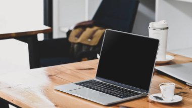 Laptop bilgisayarı ve kahve fincanını ahşap masaya koy..