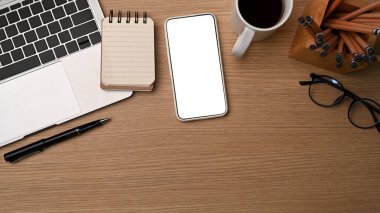 Akıllı telefon, dizüstü bilgisayar, defter ve kahve fincanını ahşap masaya koyun..