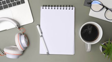 Yaratıcı çalışma alanındaki top view defteri, kahve fincanı ve kulaklık.