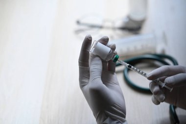 Kadın doktor elinde şırınga ve aşı şişesi tutuyor..