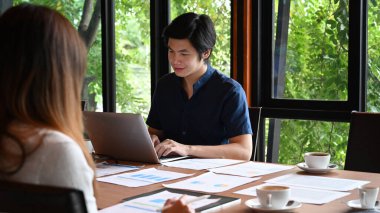 Bir grup genç iş adamı modern ofis odasında birlikte çalışıyor..