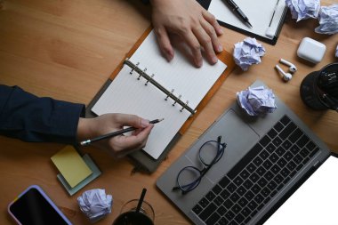 Ofis masasındaki not defterine buruşuk kağıtlarla çevrili bir iş adamı..