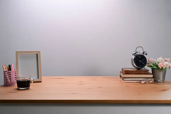 Simple workplace with books, coffee cup and photo frame on wooden table.