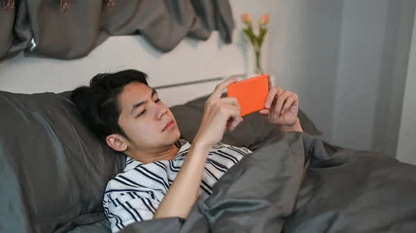 Młody Azjata Pomocą Smartfona Jego Łóżku Nocy — Zdjęcie stockowe