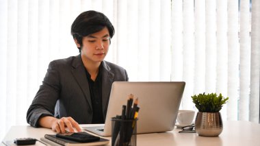 Modern iş yerinde dizüstü bilgisayarla çalışan yakışıklı bir iş adamı..