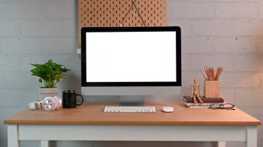 Ahşap masa üzerinde bilgisayar ve malzemelerle modern işyeri.