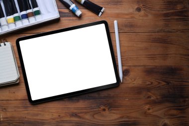 Sanatçı çalışma alanı üzerine dijital tablet, stil kalem, suluboya ve defter.