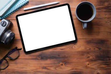 Üst görünüm dijital tablet, stilus kalem, kahve fincanı ve kamera ahşap masa üzerinde..