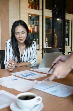 Bir grup işadamı toplantı odasında iş belgelerini inceliyor..