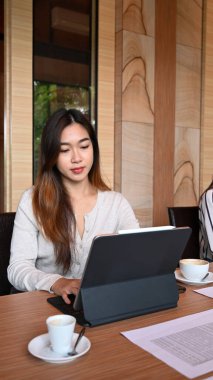 Toplantı odasında otururken bilgisayar tabletiyle çalışan genç bir iş kadını..