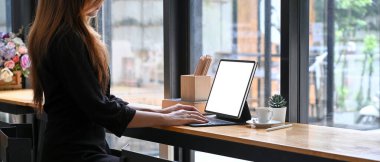 Kafede otururken bilgisayar tableti kullanan kesilmiş genç bir kadın..