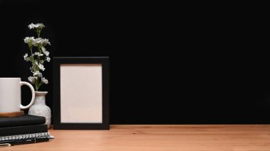 Boş çerçeve, kitaplar ve kahve fincanı ahşap masada..