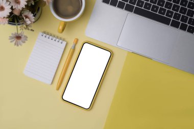 Sarı arkaplanda üst görünüm akıllı telefon, defter ve dizüstü bilgisayar.