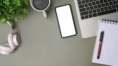 Yukarıda akıllı telefon, dizüstü bilgisayar, kulaklık ve kahve fincanı gri arka planda..