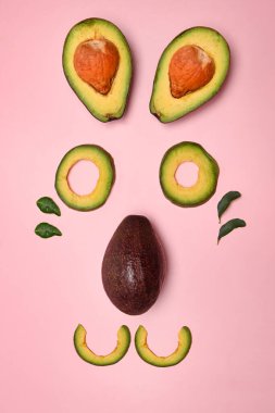 Pembe arka planda izole edilmiş taze ve dilimlenmiş avokado..