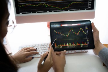 İş ekibi dijital tabletle borsa ticaretini tartışıyor ve analiz ediyor.