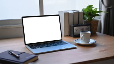 Laptop, dizüstü bilgisayar, kahve fincanı ve çiçekli ofis masası..
