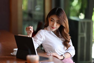 Modern iş yerinde bilgisayar tabletleriyle çalışan çekici bir iş kadını..