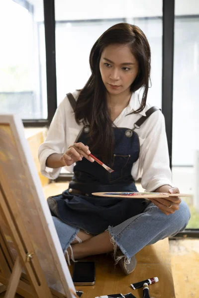美しい女性アーティストがアートスタジオの床に座り キャンバスに絵を描く — ストック写真