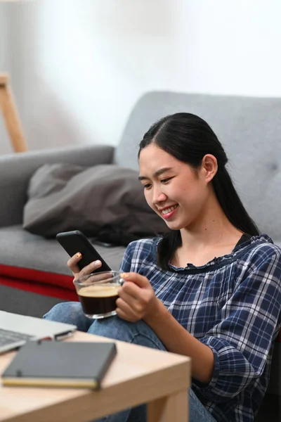 Leende Kvinna Med Smart Telefon Och Dricka Kaffe Vardagsrummet — Stockfoto