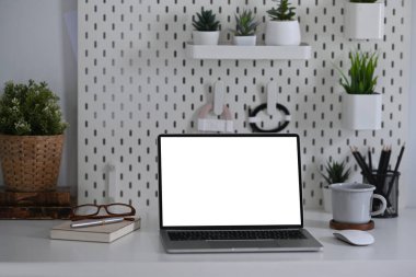 Bilgisayarın, kahve fincanının ve ev bitkisinin bulunduğu ofis masasında..