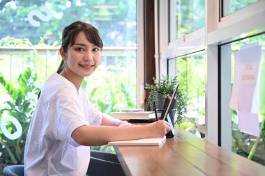 Genç Asyalı kız öğrenci evde ödev yapıyor..