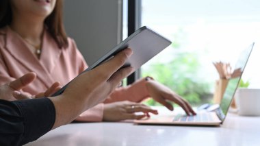 Kesilen görüntüler, dijital tablet üzerindeki finansal verileri birlikte analiz eden iş adamları.