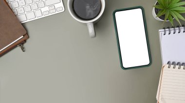 Üst görünüm cep telefonu, dizüstü bilgisayar, yeşil arka planda kahve fincanı..