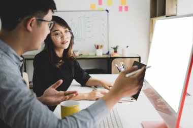 Ofiste bilgisayardaki verileri tartışan ve analiz eden iki iş adamı.