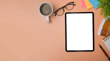 Dijital tablet, gözlük, kahve fincanı ve renk örnekleriyle yaratıcı çalışma alanı.