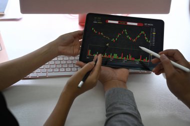 Dijital tablet üzerindeki hisse senedi verilerini analiz eden işadamları.