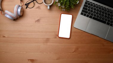 Üst görünüm, dizüstü bilgisayar ve cep telefonunu ahşap masaya yerleştirin.
