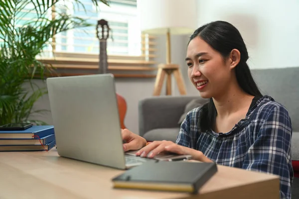 家でコンピュータのラップトップで働いている若い女性を笑顔 — ストック写真