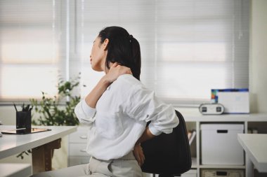 Kadın çalışan omuz ve boyun rahatsızlığından muzdarip, muhtemelen kötü duruş veya stres nedeniyle...