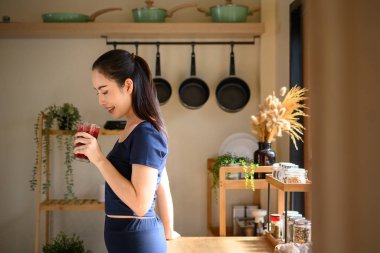 Aktif giysili Asyalı kadın antrenmandan sonra taze meyve suyu içiyor..