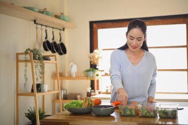 Sıcak bir mutfakta taze sebze hazırlayan bir kadın sağlıklı gıda depolama ve yemek koruma üzerine odaklanıyor...