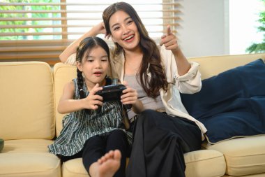 Anne kızına oyun oynamayı öğretiyor, kahkahaları paylaşıyor ve eğlenceli dijital oyun saatleriyle öğreniyor..