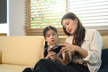 Anne kızına oyun oynamayı öğretiyor, kahkahaları paylaşıyor ve eğlenceli dijital oyun saatleriyle öğreniyor..