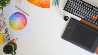 Renk paleti, dijital tablet ve not defteri çizim logosu tasarımı ile beyaz masadaki yaratıcı çalışma alanının üst görünümü.