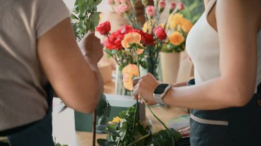 Yakından insanlar yaratıcı bir atölyede çiçek düzenlemeyi öğreniyorlar, takım çalışması ile renkli buketler yapıyorlar..