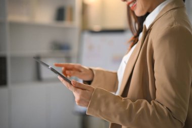 Kesilen iş kadını tablet kullanarak çizelgeleri ve verileri inceleyerek güven ve memnuniyeti gösteriyor..