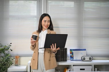 Modern ofiste dizüstü bilgisayar kullanan orta yaşlı iş kadını, özgüven ve profesyonellikle çalışmaya ve analize odaklanıyor..