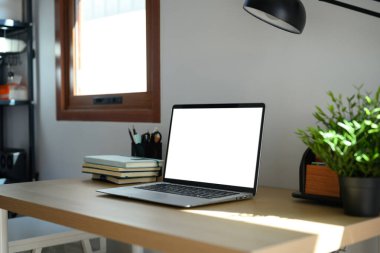 Yan görünüm açık dizüstü bilgisayar ve ofis nesnesi tahta masada..