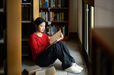 lise öğrencisi kız Kütüphanesi'nde kitap okumak.