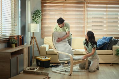 Genç çift evde yeni koltuk montajı yapıyor, DIY mobilya projesinde takım çalışması..