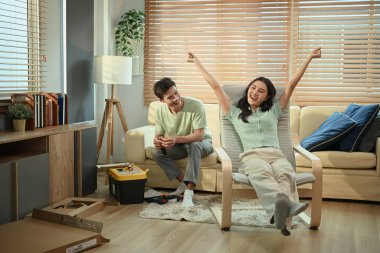 Mobilya montajını bitirdikten sonra kutlama yapan mutlu çift, DIY ev projesinde başarı.